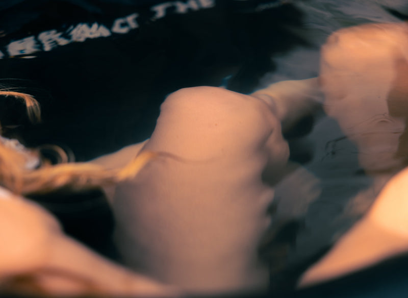 Wavey and blurry closeup of a womans knees under the water in a LUMI ice bath
