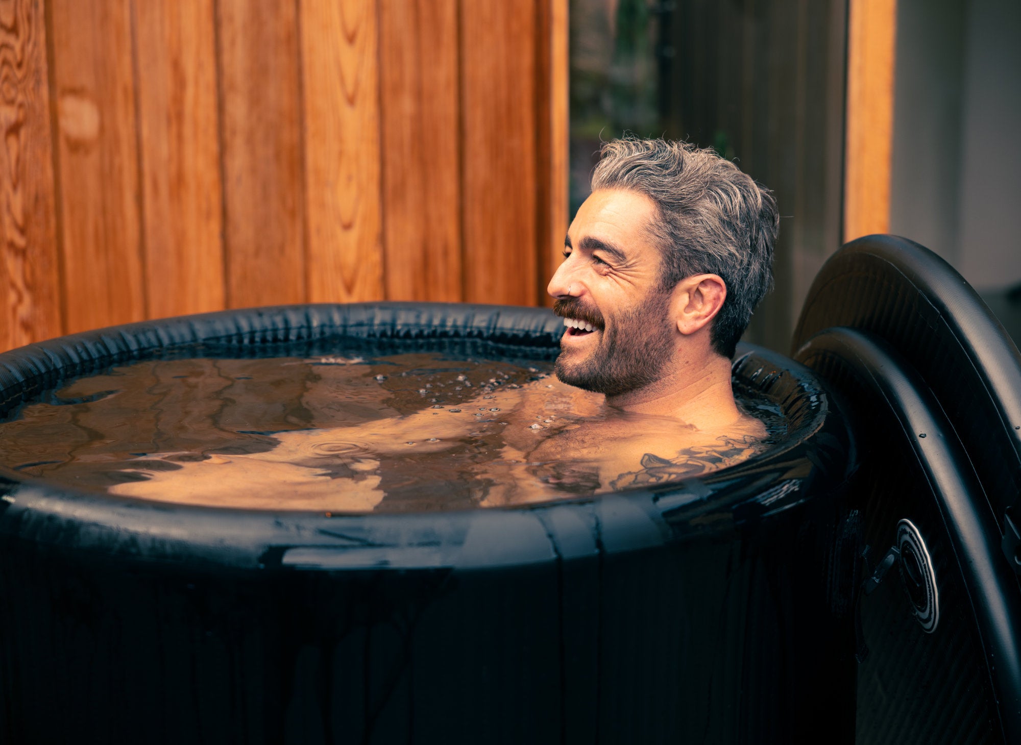 Man with gray hair and beard enjoying a LUMI Pro 8 ice bath, outdoor setting