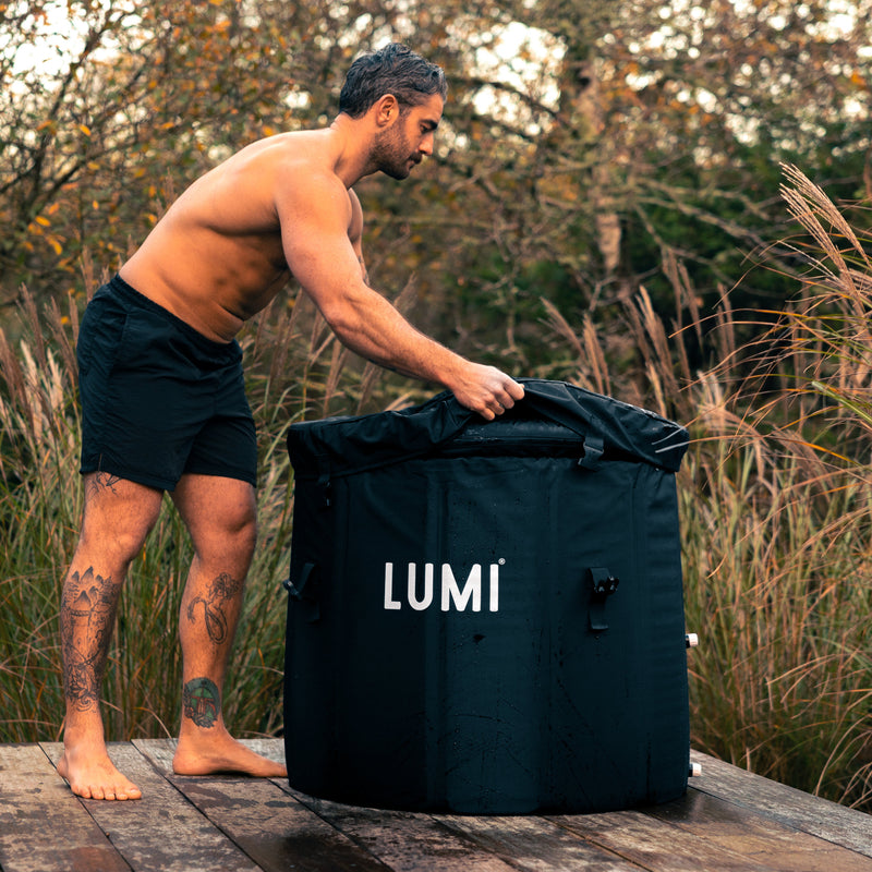 Man removing the weather cover from the LUMI MAX Ultra ice bath, outdoor setting