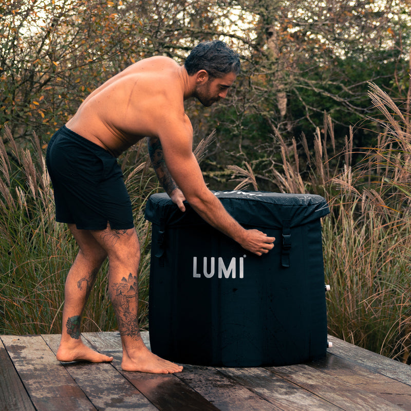 Photo of a man removing the weather cover on the LUMI Pod 2 ice bath, in an outdoor setting.