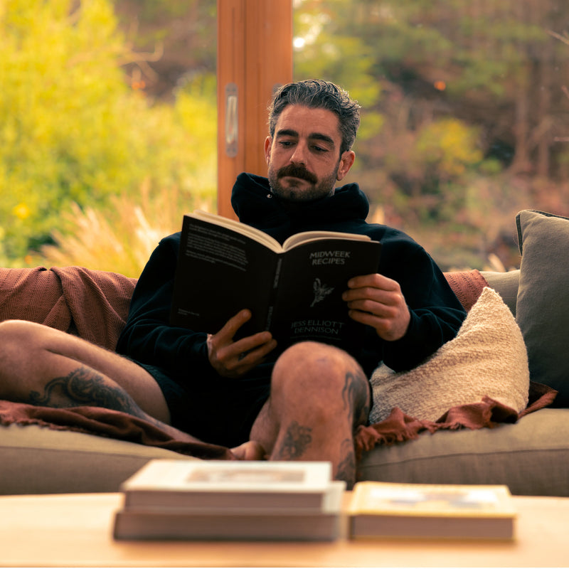 Photo of a man sat relaxing and reading after a cold water therapy and sauna session with LUMI products.
