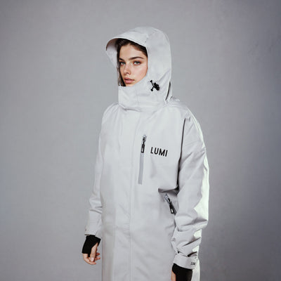 PRO DUO Changing Robe in grey, featuring a hooded design with LUMI branding, waterproof exterior, and front zip pocket. Studio shot showcasing the robe's sleek Nordic style, adjustable hood, and technical outerwear details against a grey background.