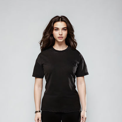 Model wearing Women's LUX T-Shirt Black Wash against grey background, showcasing classic crew neck design, short sleeves, and vintage black wash finish. Premium cotton t-shirt styled in a relaxed fit with simple, minimalist aesthetic.