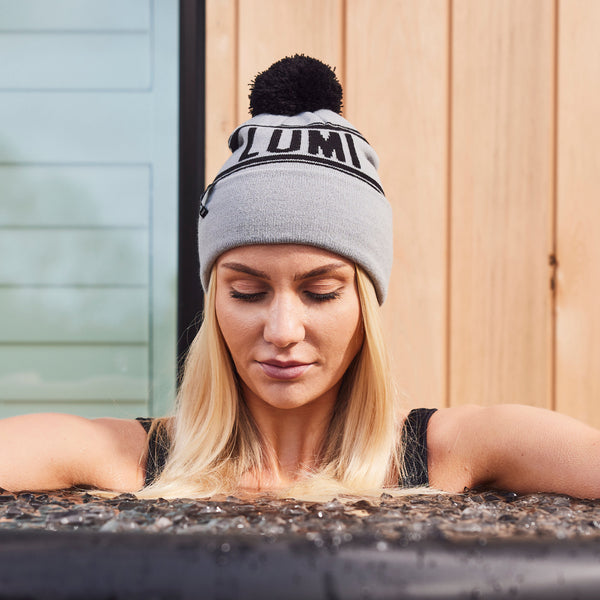 A woman enjoying an ice bath wearing a LUMI Bobble Hat in Grey 