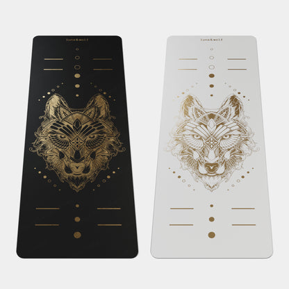 Eco Wolf Yoga Mat - Gold Edition features a premium black and white mat set with intricate golden wolf head design, alignment markers, and metallic geometric patterns. Each mat displays a symmetrical, mystical wolf illustration surrounded by decorative dots and lines for positioning guidance.