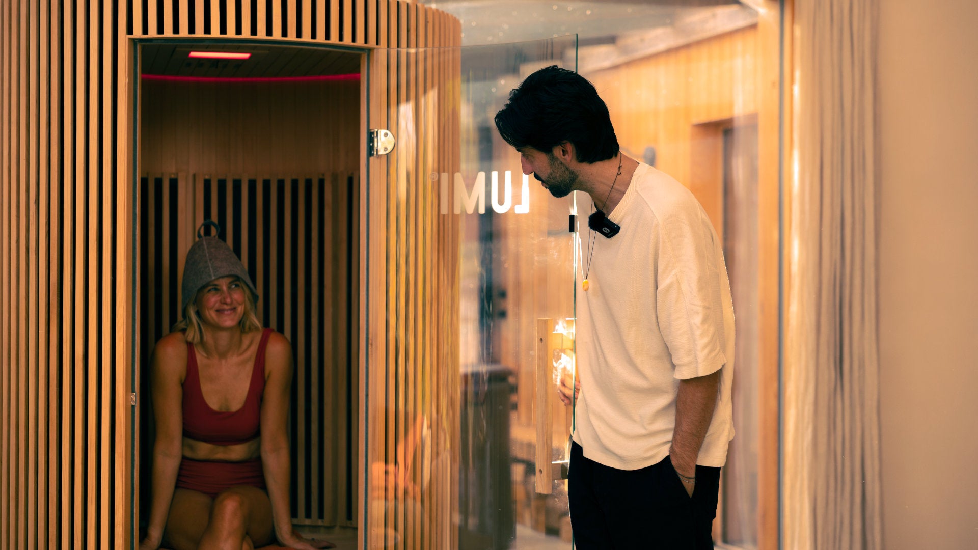 Gavin, director and founder of LUMI chatting with a smiling woman sat in the LUMI Sauna PRO