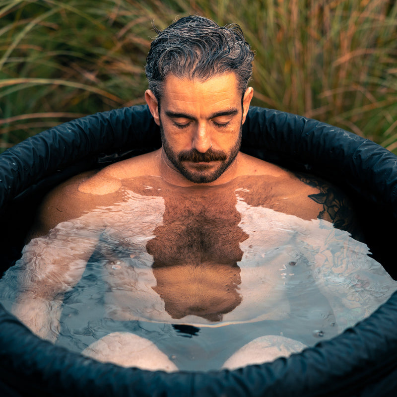 Man sat in the LUMI MAX Ultra ice bath, eyes closed and focused on recovery, outdoor setting