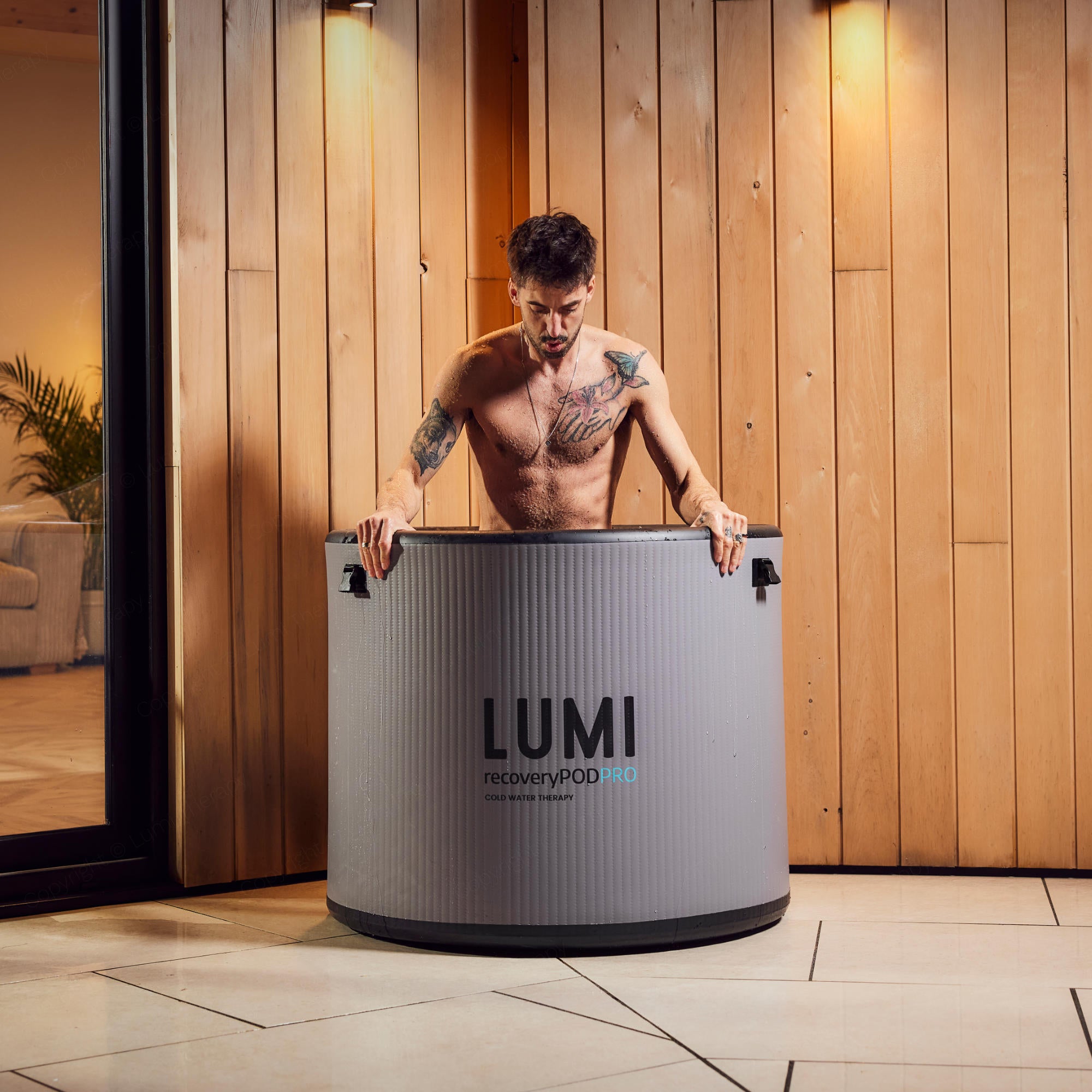 A man getting into a LUMI Therapy Recovery Pod Pro Ice Bath