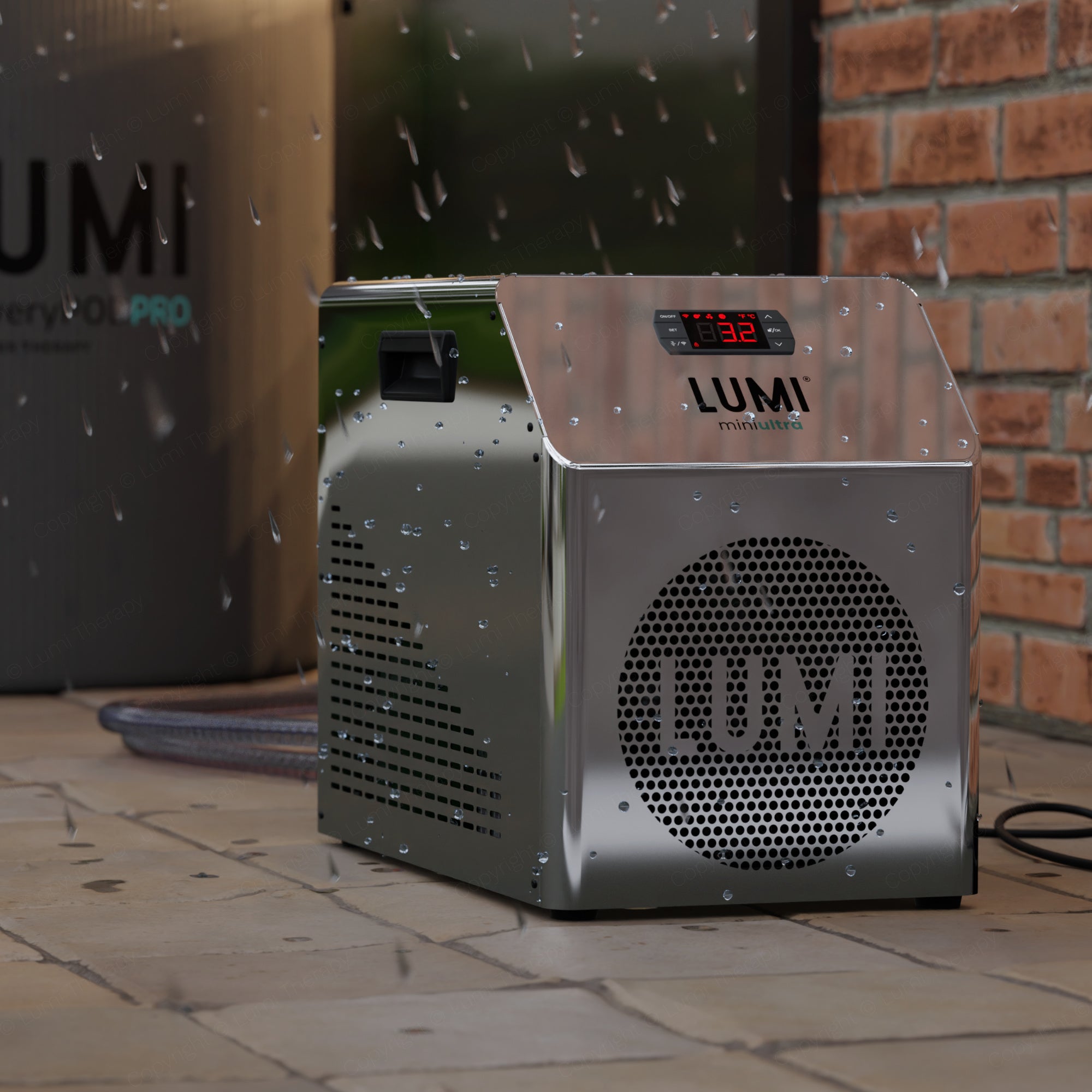 LUMI miniULTRA Chiller Refurbished model with mirror-finish stainless steel exterior, digital temperature display, and perforated LUMI logo design, shown with water droplets on surface, positioned on stone tiles against brick wall background