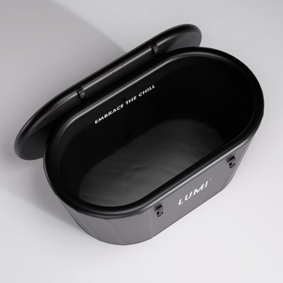 Open LUMI Recovery Duo PRO Ice Bath in black with lid open showing smooth interior and "Embrace The Chill" text inside