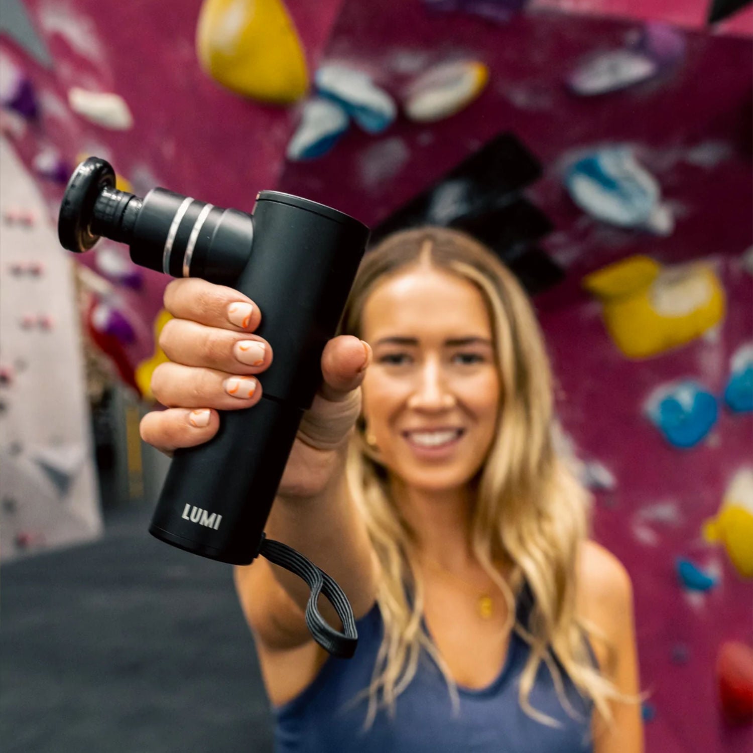 A woman holding up a Lumi miniPRO massage gun